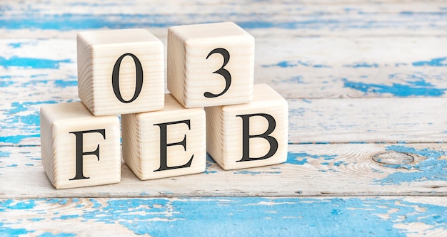 February 3rd. Wooden cubes with date of 3 February on old blue wooden background.