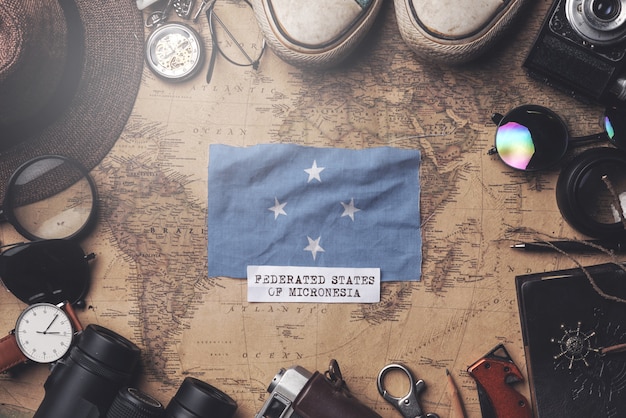 Federated States of Micronesia Flag Between Traveler's Accessories on Old Vintage Map. Overhead Shot