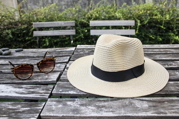 Fedora hat, sunglasses on outdoor wooden table chilling day