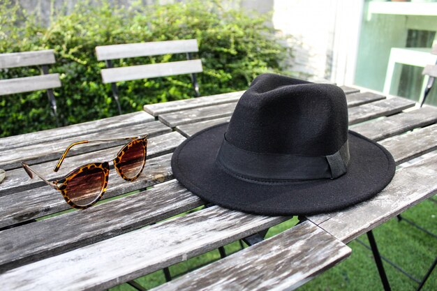 Foto cappello e occhiali da sole fedora sul tavolo di legno all'aperto