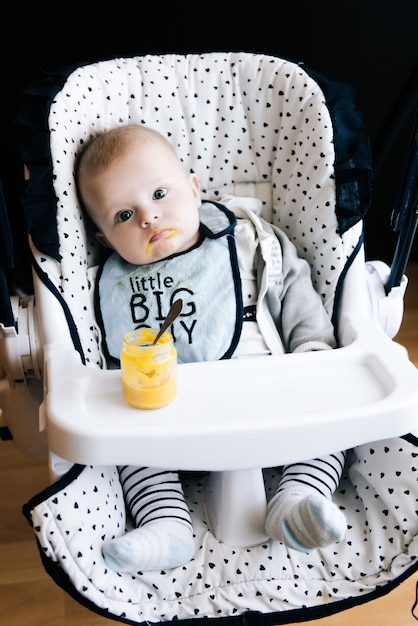 Photo feeding. adorable baby child eating with a spoon in high chair. baby