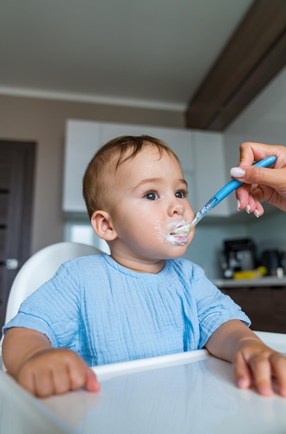 Feeding baby food to baby Small child sits on a chair and eating with spoon