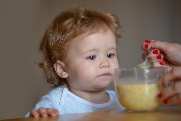 子供のためのフルーツピューレの健康的な栄養で彼女の赤ん坊の息子を養う赤ん坊の母を養う