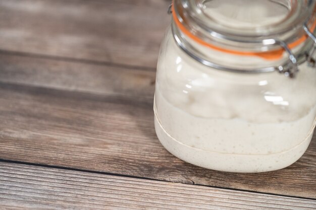 Feeding sourdough starter in a glass mason jar for baking artisan bread.