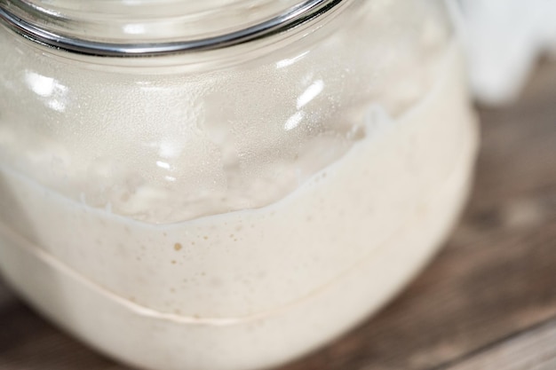 Feeding sourdough starter in a glass mason jar for baking artisan bread.