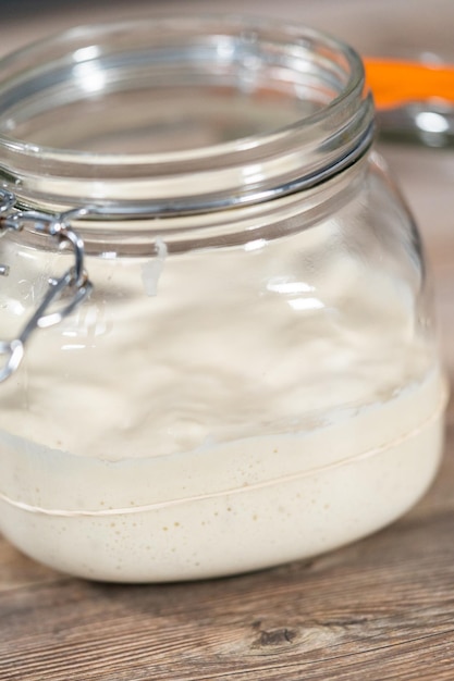 Feeding sourdough starter in a glass mason jar for baking artisan bread