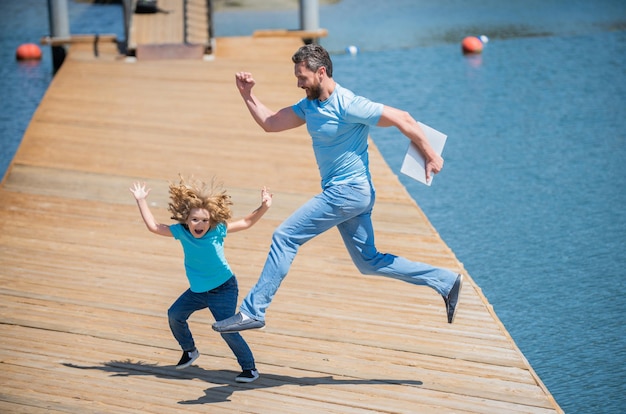 Feel free to jump Energetic father and son jump on pier Family fun