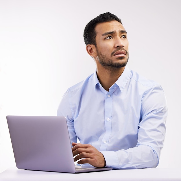 Feeling a bit fearful of the future Studio shot of a young businessman looking worried while using a laptop against a white background