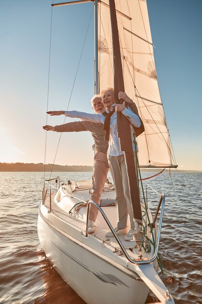 Feeling carefree happy senior couple stretching hands out against the sky and smiling while