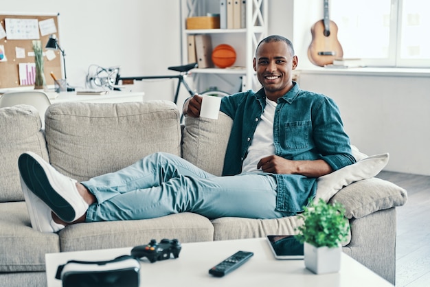 Feeling comfortable. Handsome young African man looking at camera and smiling while sitting indoors