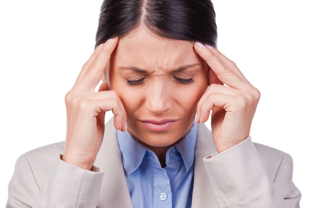 Feeling exhausted. Depressed young businesswoman touching her face and keeping eyes closed