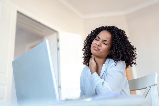 Feeling exhausted Frustrated young woman looking exhausted and massaging her neck while sitting at her working place