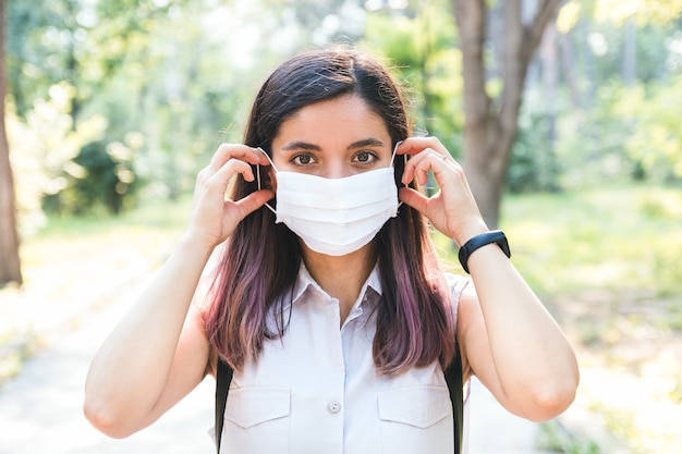自由自在。医療マスクを削除して元気に呼吸する公園で一人で若い女性