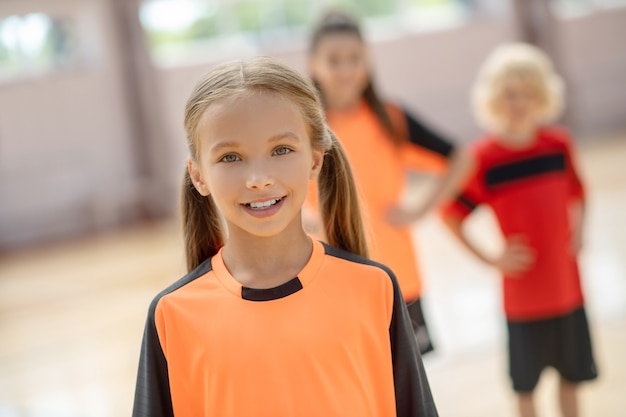 Feeling good. Cute girl in orange tshirt smiling positively