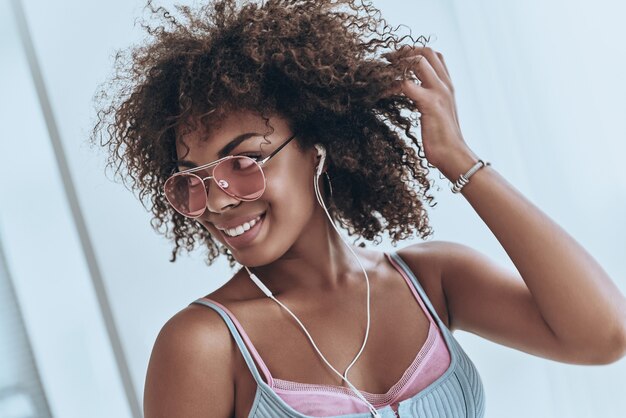 Feeling the groove. Attractive young African woman listening music and smiling while spending time at home