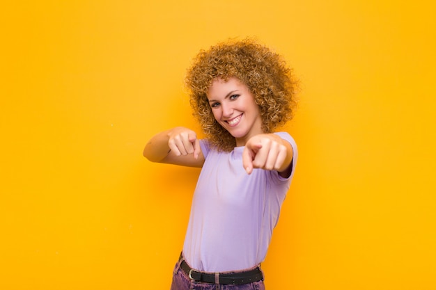 feeling happy and confident, pointing to camera with both hands and laughing, choosing you