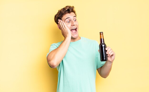 Feeling happy, excited and surprised, looking to the side with both hands on face. beer bottle concept