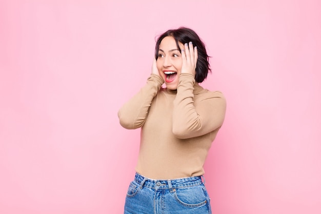 Sentirsi felici, eccitati e sorpresi, guardando di lato con entrambe le mani sul viso