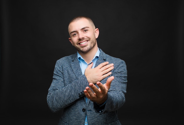 Foto sentirsi felici e innamorati, sorridendo con una mano vicino al cuore e l'altra allungata in avanti