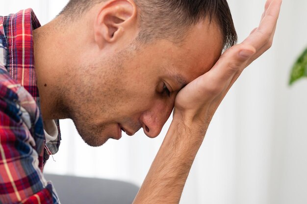 Foto sentirsi senza speranza. giovane uomo barbuto depresso che tiene gli occhi chiusi e si tocca il viso