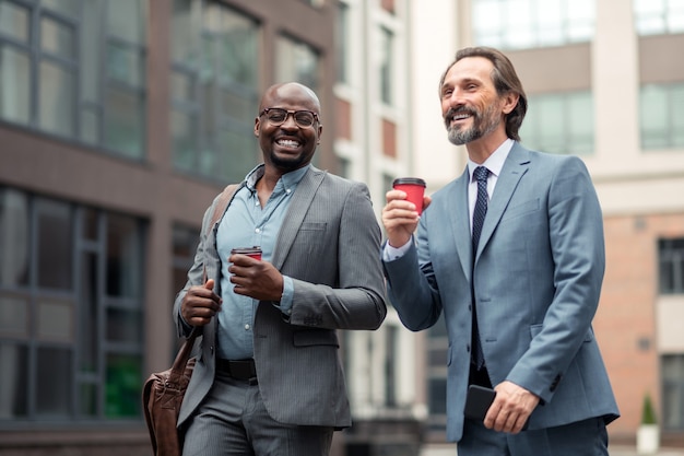 Feeling motivated. Cheerful businessmen drinking coffee feeling motivated in the morning