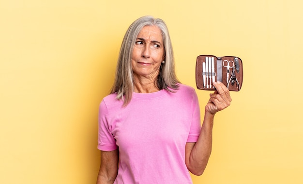 Photo feeling sad, upset or angry and looking to the side with a negative attitude, frowning in disagreement holding a nails tools case