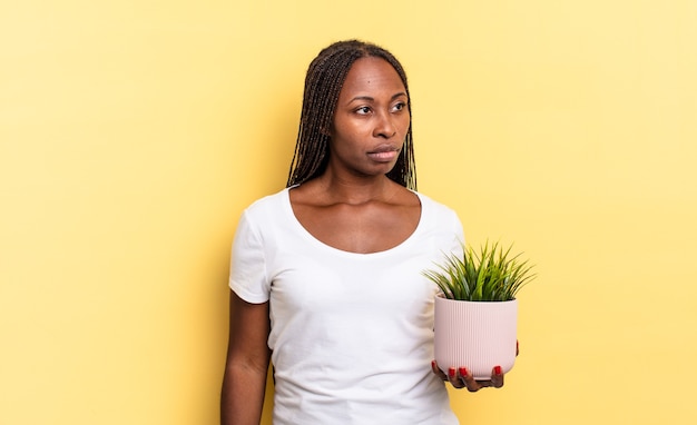 Feeling sad, upset or angry and looking to the side with a negative attitude, frowning in disagreement holding a plant pot