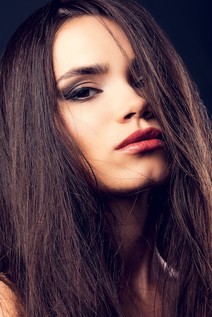 Feeling seductive. Attractive young woman looking at camera and covering half of face by hair 