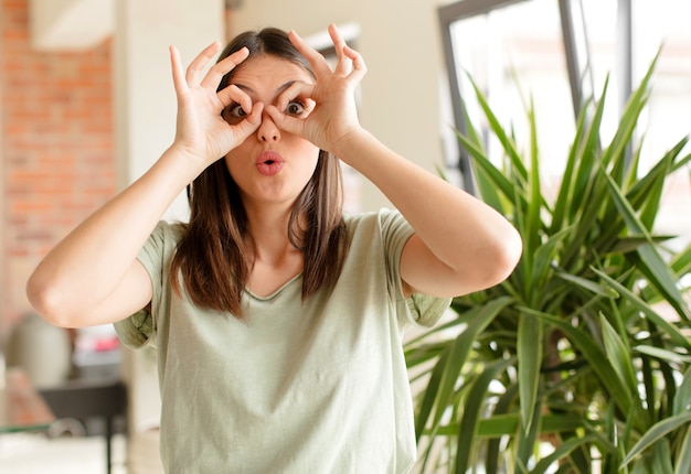 feeling shocked amazed and surprised holding glasses with astonished disbelieving look