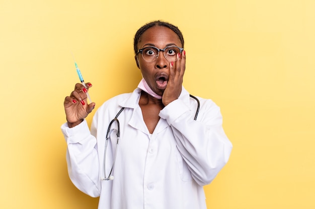 Feeling shocked and scared, looking terrified with open mouth and hands on cheeks. physician and syringe concept