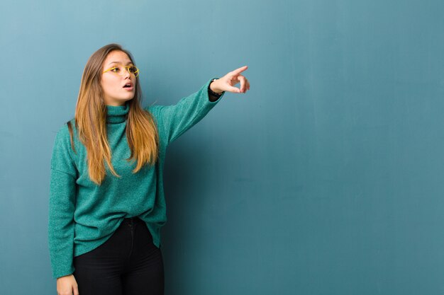 Photo feeling shocked and surprised, pointing and looking upwards in awe with amazed, open-mouthed look