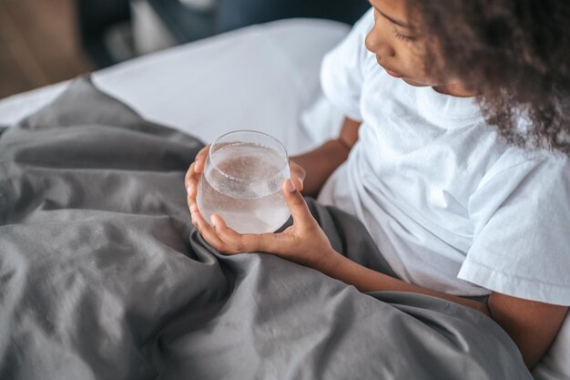 Feeling sick. A girl taking a pill while lying in bed and feeling unwell