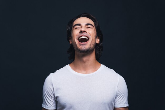 Feeling so happy. Portrait of happy young man keeping mouth open and eyes closed while standing 