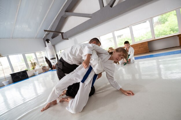 Feeling some pain. Blonde-haired schoolgirl feeling some pain while practicing throw with aikido teacher