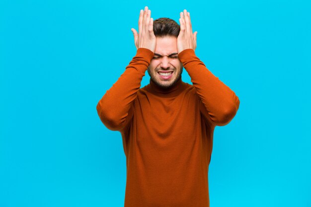 Foto sentirsi stressati e ansiosi, depressi e frustrati dal mal di testa, alzando entrambe le mani alla testa