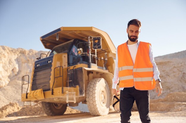 Foto sensazione di stanchezza in piedi contro il camion di trasporto l'uomo in uniforme lavora nella cava durante il giorno