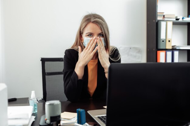 Feeling unwell business woman in a medical mask Office lady worker sick at workspace in office