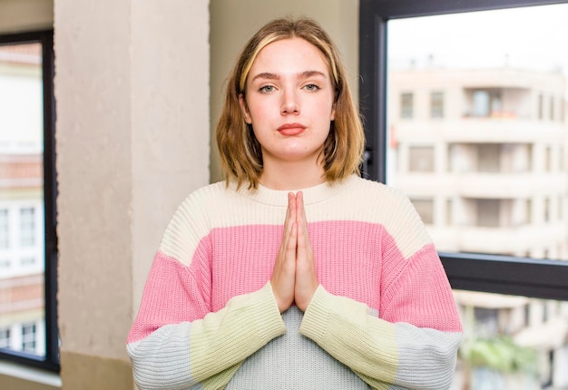 Photo feeling worried hopeful and religious praying faithfully with palms pressed begging forgiveness