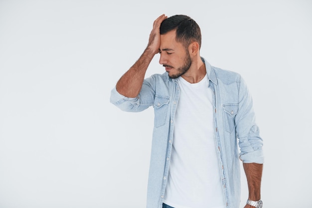 Feels bad Young handsome man standing indoors against white background