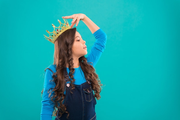 Feels like queen. Kid wear golden crown symbol of princess. Every girl dreaming to become princess. Lady little princess. Girl cute baby wear crown while stand blue background. Childhood concept.