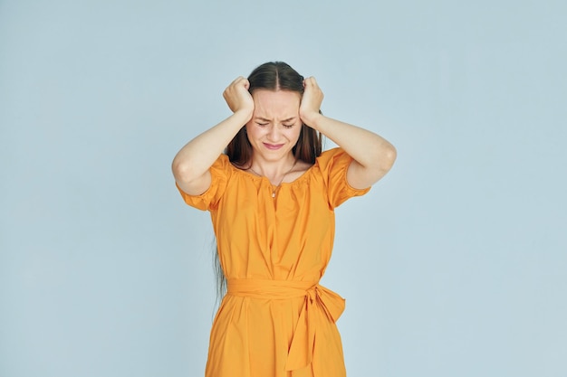 Feels pain Young woman in casual clothes standing indoors in the studio