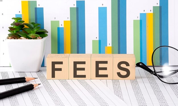 차트, 안경, 연필로 나무 블록에 쓰여진 FEES 단어