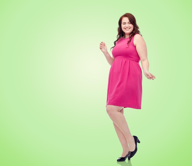 feest en mensen concept - lachende gelukkige jonge plus size vrouw poseren in roze jurk dansen over groene natuurlijke achtergrond