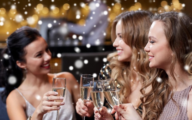 feest, vrienden, nieuwjaar, kerstmis en wintervakantie concept - gelukkige vrouwen met champagneglazen op vrijgezellenfeest in nachtclub over sneeuw