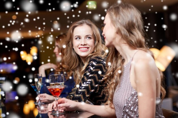 feest, vrienden, vrijgezellenfeest en vakantieconcept - gelukkige vrouwen die champagne en cocktails drinken in de nachtclub