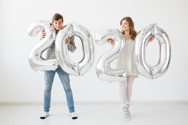 Feestdagen, feestelijk en feestconcept - Happy liefdevolle paar kussen en houdt zilveren 2020 ballonnen. Nieuwjaarsviering
