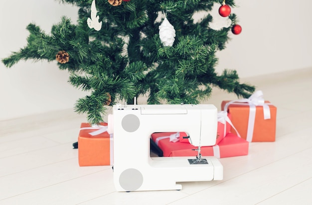 Feestdagen, kledingontwerp en cadeauconcept - Naaimachine als cadeau onder de kerstboom.