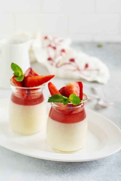 Feestelijk dessert met bessengelei, vanille panna cota en verse aardbei op grijze betonnen tafel achtergrond. Selectieve aandacht.