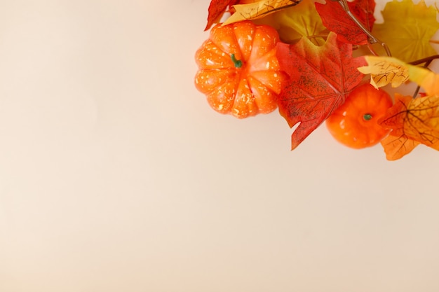 Feestelijk herfstdecor met pompoenen en bladeren op een beige ondergrond