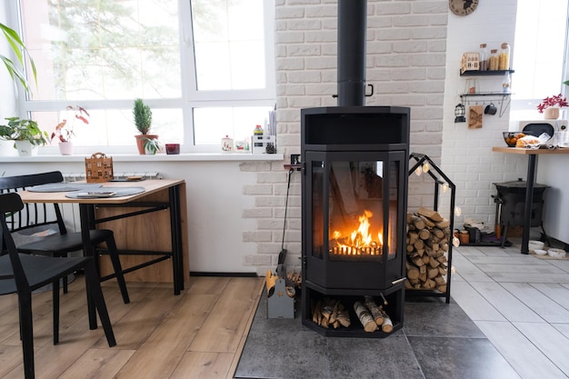 Foto feestelijk interieur van het huis is versierd voor kerstmis en nieuwjaar in loftstijl met zwarte kachel, open haard, kerstboom, warme studiokamer met witte keuken, brandend hout, gezellig en verwarming van huis